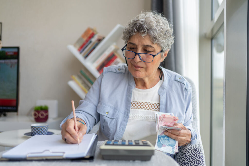 Senior Woman Counting Money And Doing Finances At Home